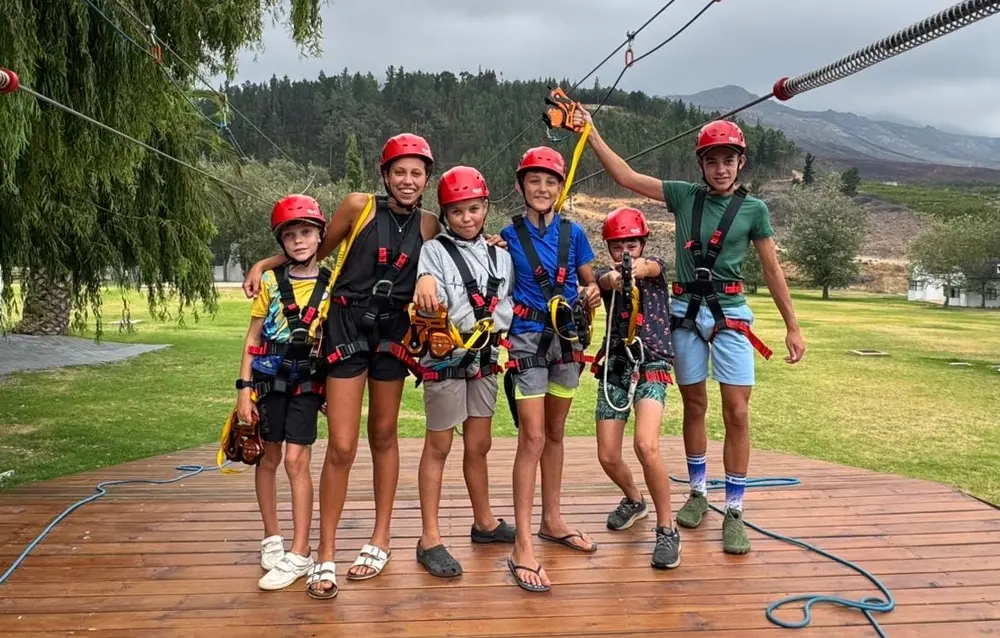 A group of kids in helmets and harnesses ready to ride the dual zipline at Houw Hoek Zipline